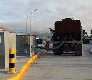 A hauler uses a Portalogic waste dump station, which collects data about the load and syncs with Portalogic Management Software.
