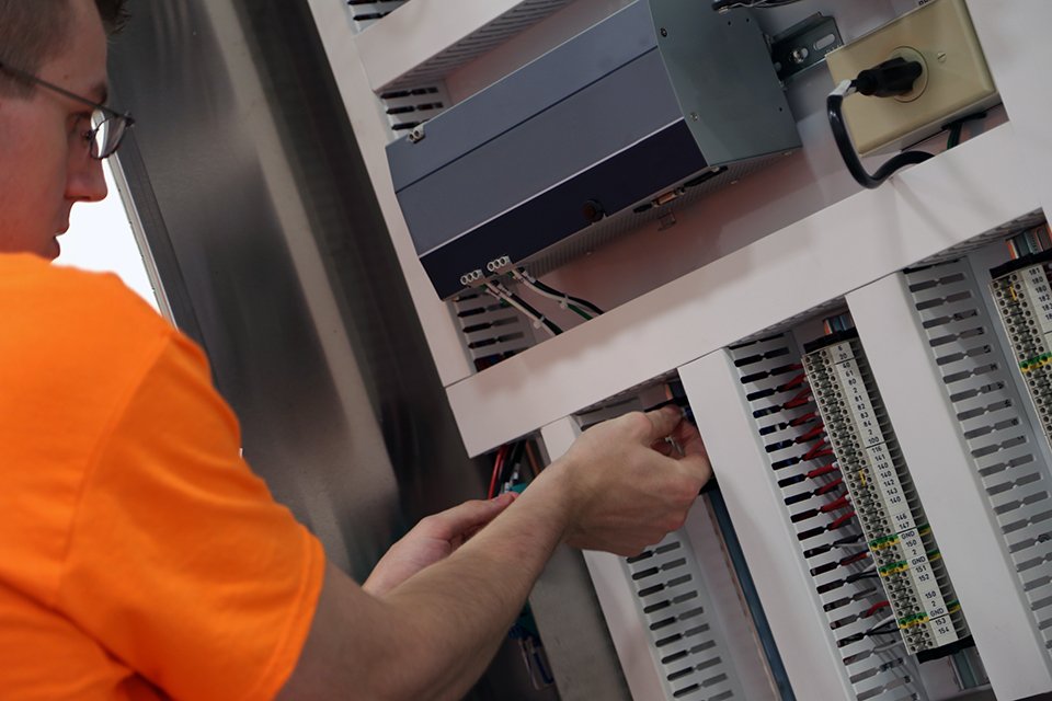 An EleMech employee testing wire connections in our modern and clean facility.